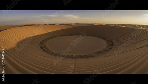Desert stadium dune sand arena circular dune natural amphitheater golden desert aerial landscape abstract pattern remote wilderness sunset light minimal nature formation gently curves warm sunset