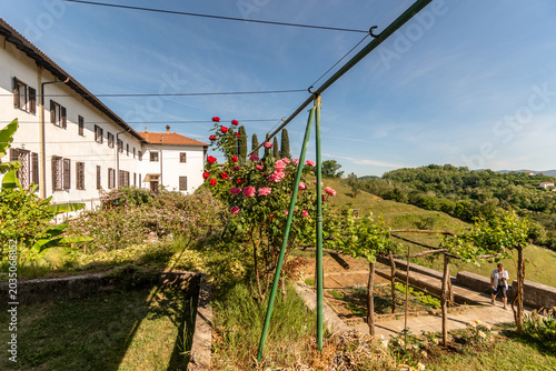 Il monastero sloveno francescano di Kostanjevica o Castagnevizza con in primo piano parte della sua collezione di rose Bourbon rosse,  in primavera 