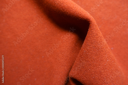 Texture of simple reddish orange felt fabric in soft folds
