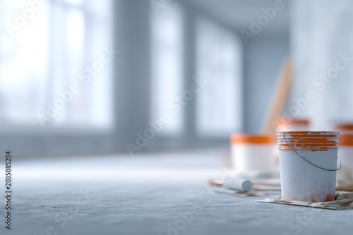 Paint bucket and roller on a concrete floor at a construction site. Commercial property renovation and building interior painting. Industrial repair and maintenance concept