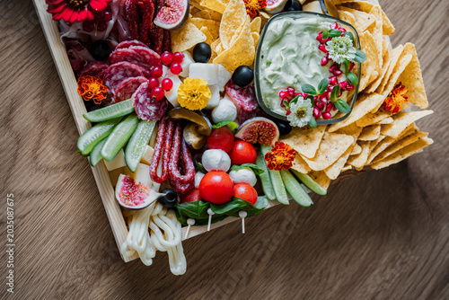 Bild auf Leinwand Gourmet charcuterie board with assorted cheeses, cured meats, fresh fruit, crackers, and snacks