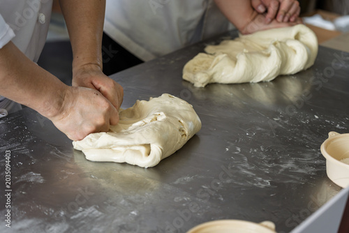 Baker hand kneading dough on workbench