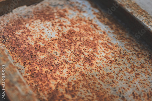 Close-up of rusted metal surfaces, including rusty nails and sheet metal in various tones of corrosion. Textured abstract industrial background with warm rusty colors.