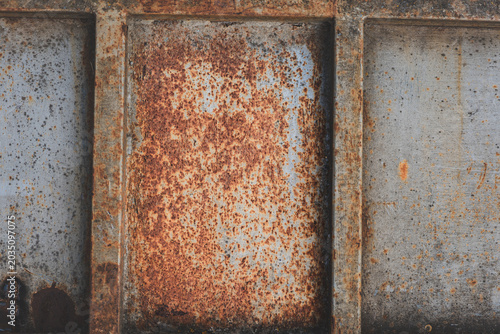 Close-up of rusted metal surfaces, including rusty nails and sheet metal in various tones of corrosion. Textured abstract industrial background with warm rusty colors.