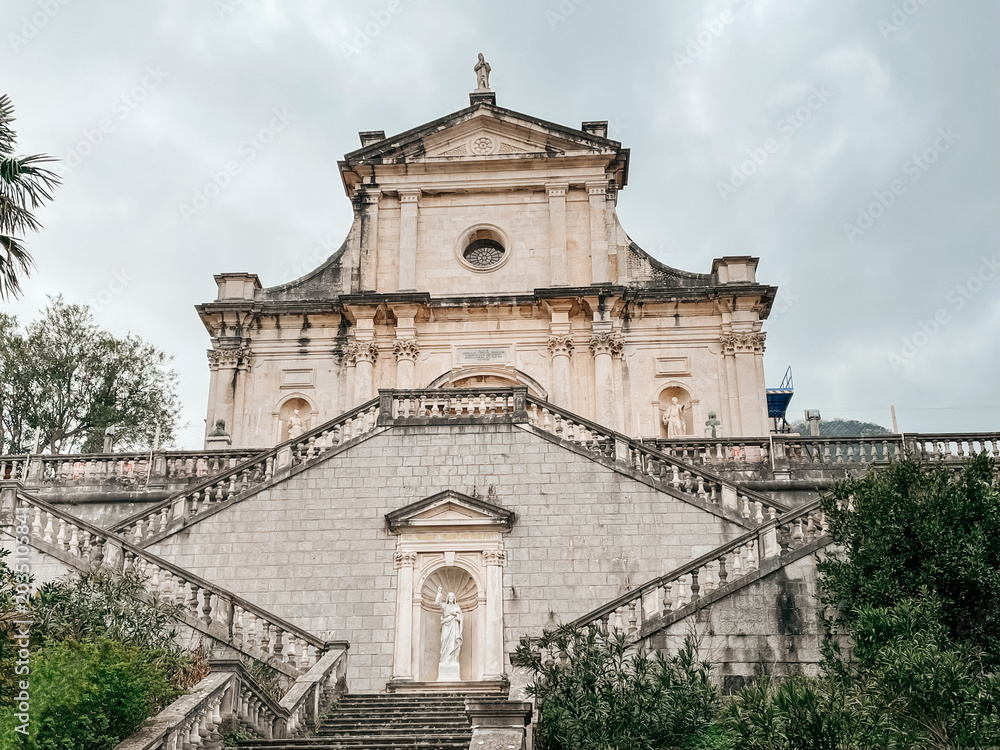 Fototapeta premium Grand Stone Steps Leading Kotor Church, Baroque Facade Framed By Overcast Sky, Worn Marble Balustrades, Empty Plaza With Cobblestone Pavement,