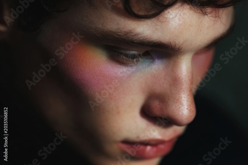 Close-up portrait of a young man with soft rainbow blush and glowy skin for beauty background and editorial design
