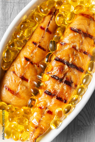 Smoked mackerel fillets with cod liver oil capsules in a white dish. Healthy Omega 3 diet concept