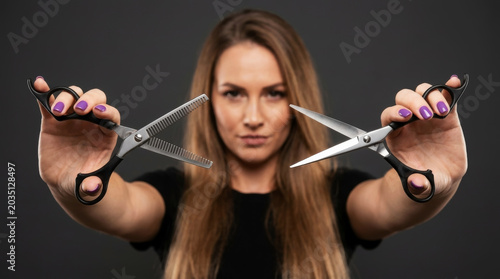 Confident Female Hairdresser Holding Professional Haircutting Scissors and Thinning Shears Towards the Camera Blurred Background