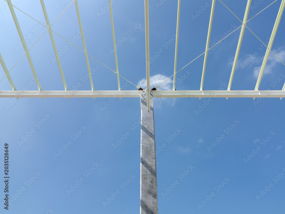 Fototapeta premium Modern steel roof structure supported by concrete columns stands prominently against clear blue sky, showcasing contemporary industrial architecture and engineering design.