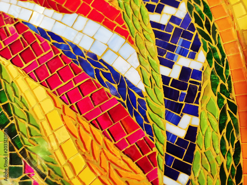 Close-up of a colorful artistic mosaic made of glass tiles in different shapes and sizes. Abstract pattern, vibrant colors, detailed texture, and handcrafted design.