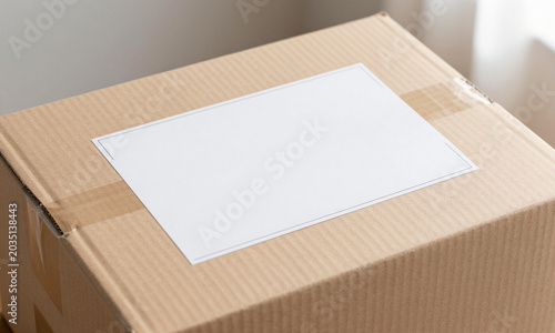 captures empty brown cardboard box soft morning light featuring blank white shipping label prominently displayed