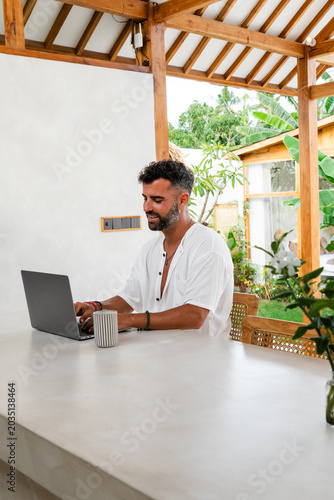 Man typing on a laptop, enjoying a tropical remote work lifestyle outdoors