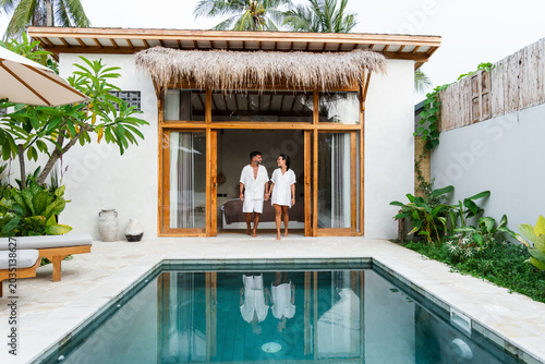 Couple walking from a luxury villa suite to a private swimming pool, holding hands