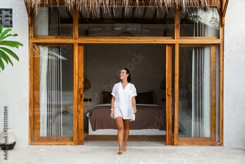 Woman enjoying tropical vacation entering luxury villa bedroom