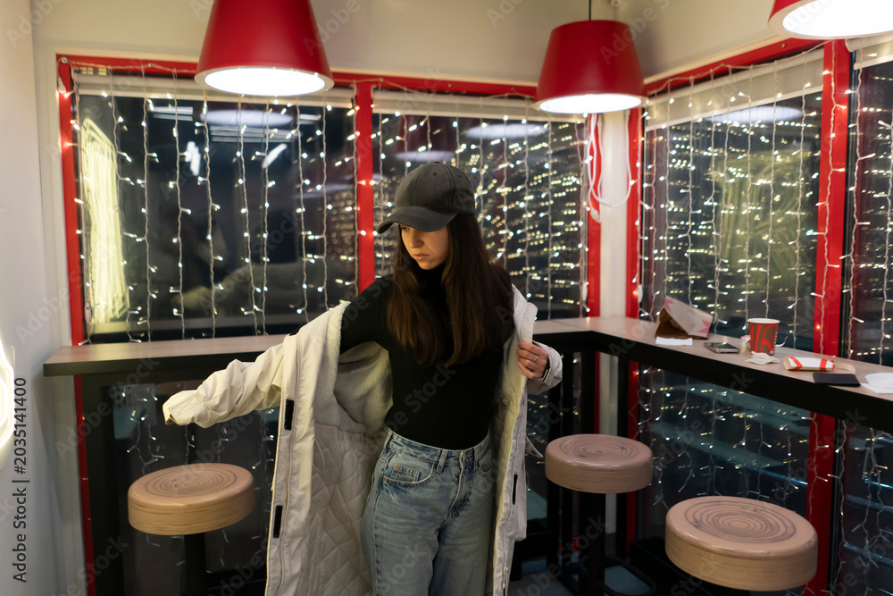 Φωτογραφία A person stands in a cafe putting on a coat while sitting at a table surrounded