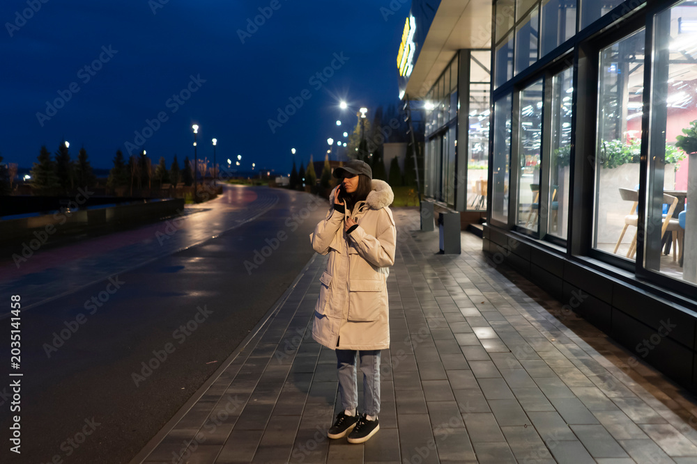 Foto Person wearing a coat is outside on a quiet street while it is getting dark