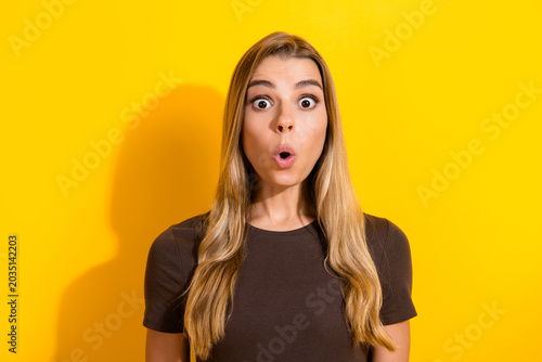 Fotografía Surprised young woman with wide eyes and open mouth against a bright yellow back