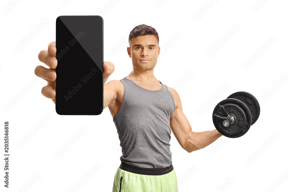 Naklejka premium Young man holding a dumbbell and showing a smartphone with blank screen