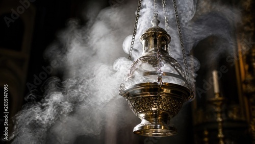 Hanging lantern releases smoke in dimly lit space during an evening ceremony in an old building
