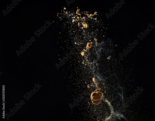 Golden Powder Fragments Exploding in Dark Black Background