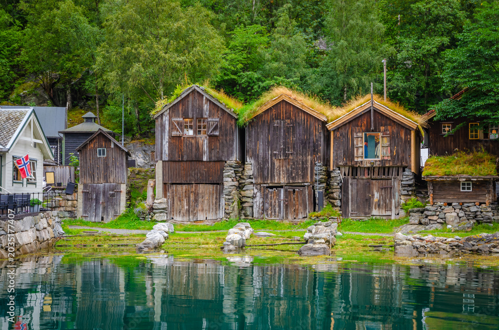 Fototapeta premium Old traditional houses on the coast of Geirangerfjord in town Geiranger, one of the most beautiful fjords in Norway