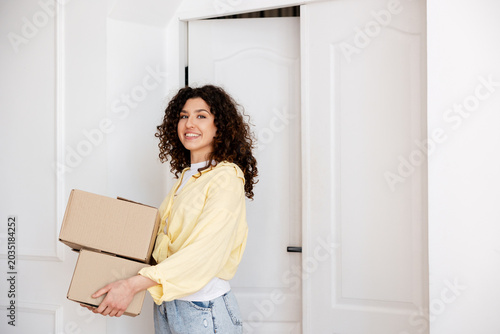 Happy woman relocating home carrying cardboard boxes