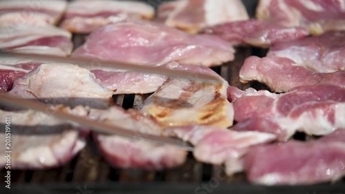 Raw meat on grill close up time lapse, man turn pieces with tongs, fat sizzling on heat