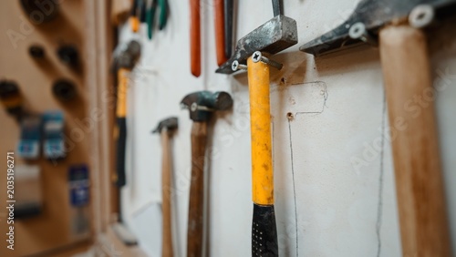 Obraz na plátne Hammers and other work tools neatly arranged on a workshop wall