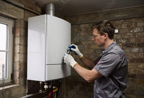 Technician adjusting condensing boiler in old community basement