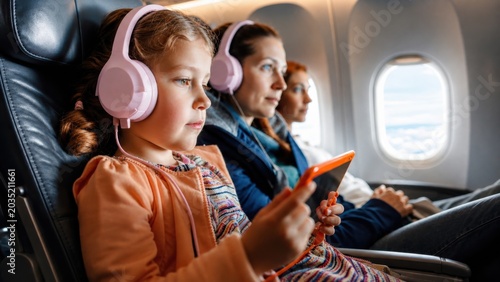 Child Using Tablet and Headphones During Family Air Travel