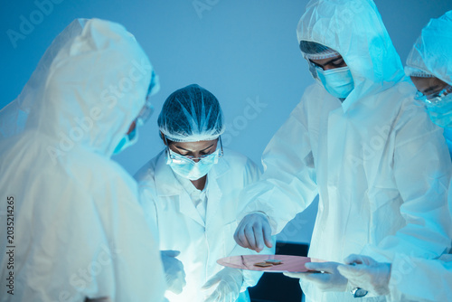 Team of tech engineer in cleanroom suit handle silicon wafer and microchip. Laboratory expert work together on semiconductor electronic component inspection for microelectronics research