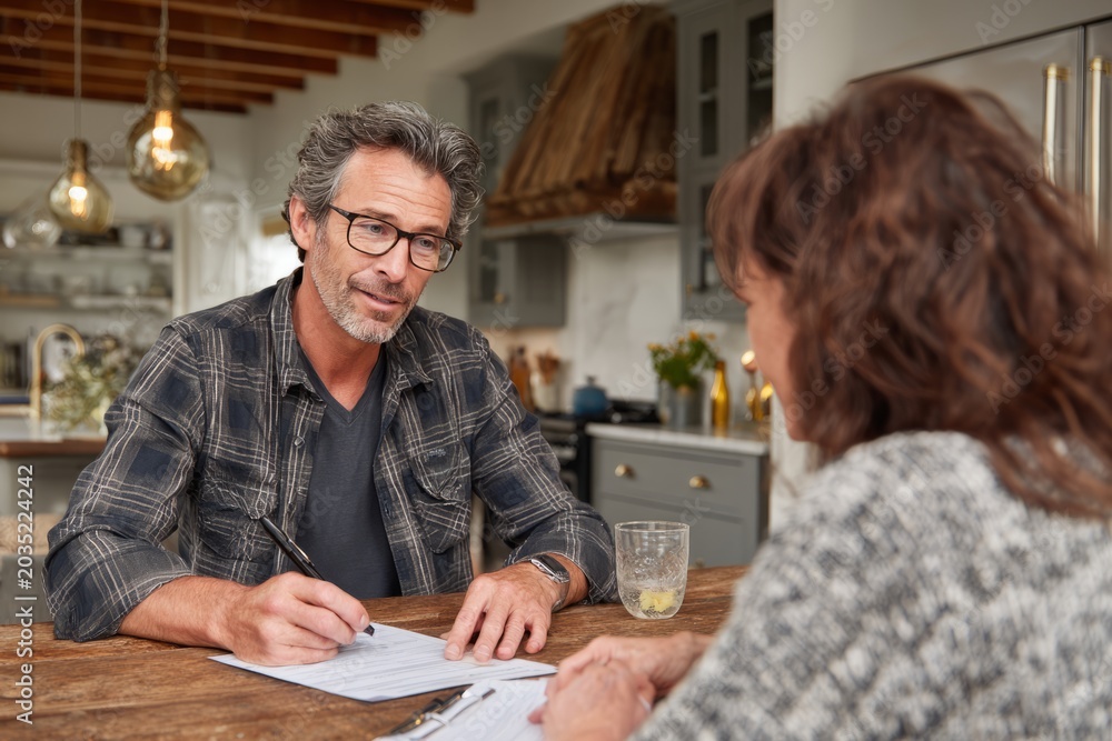 Naklejka premium Solar consultant explaining home panel proposal to homeowner at kitchen table