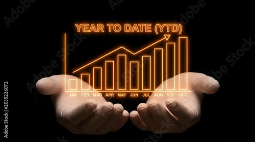 Hands holding glowing orange year to date YTD business growth chart on black background.