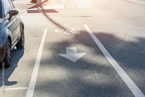 Bicycle lane along a street  in a city centre on a sunny autumn day. Symbols in the shape of a person riding a cycle and an arrow are painted on the tarmac.