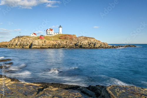 View of Nubble Lighthouse under clear blue sky in autumn. Cape Neddick, ME, USA.