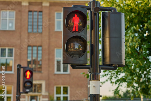 Red Pedestrian Signal Stands Tall Amidst the Vibrant City Center of Amsterdam, Guiding Footsteps Safely Across the Bustling Streets