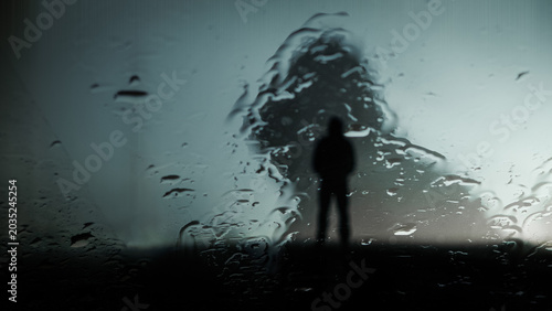 A double exposure of a hooded figure, silhouetted against a ghost like person