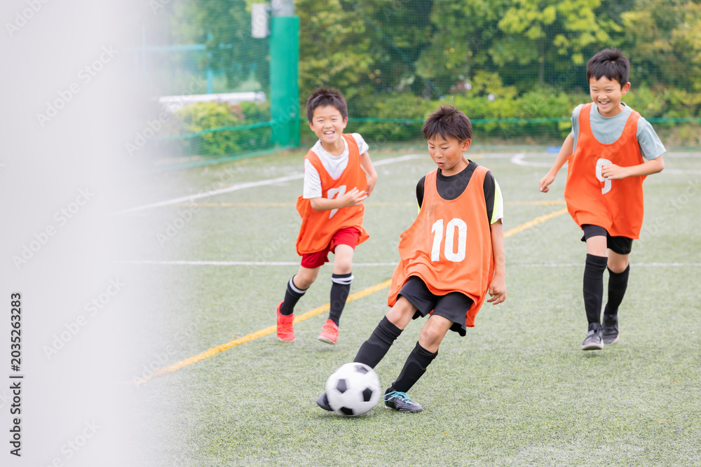 Naklejka premium ドリブルの後シュートでゴールを狙うサッカー少年たち