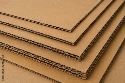 Stacked corrugated cardboard sheets close up showing layered texture, packaging material concept, recyclable paper board, industrial material background.