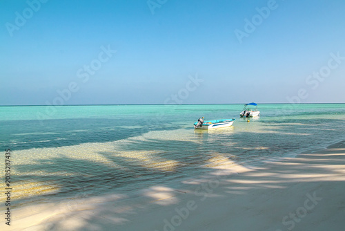 Cuadro en lienzo Maldives beach with palm shadows and boats, selective focus