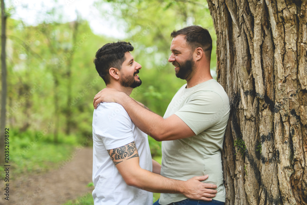 Fototapeta premium A Portrait of a happy gay couple outdoors in forest background
