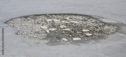 Tableau sur toile A large pothole in the asphalt pavement filled with crushed stone