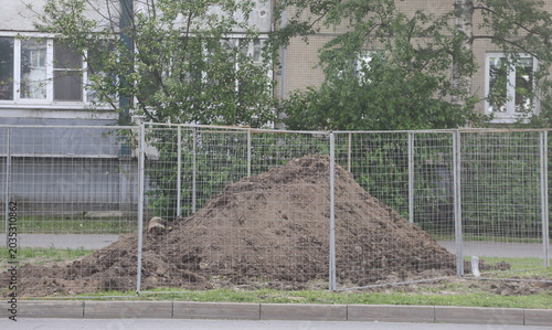 Photos A pile of soil dug up on the lawn is surrounded by a chain-link fence