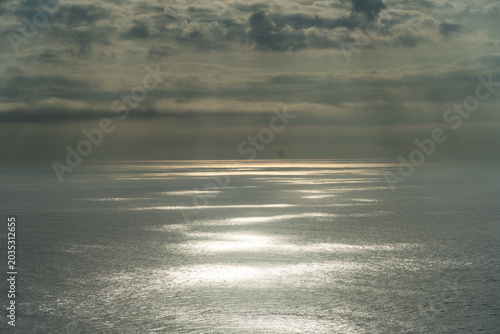 Φωτογραφία A dramatic view of sunlight breaking through heavy clouds over the expansive oce