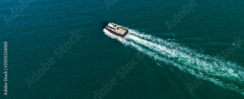 Overhead aerial of a small pilot boat speeding and leaving a prominent white wake