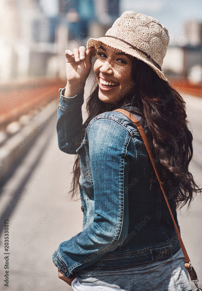 Fototapeta premium Smile, woman and walk for travel in city for adventure, tourist abroad and summer holiday. Portrait, female person and urban bridge for sightseeing town, sunshine and weekend break for vacation trip