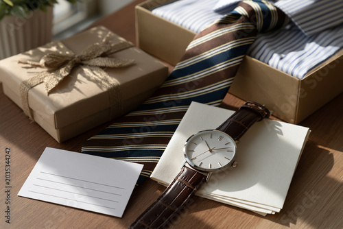 Father’s Day gift with a watch, tie, and card on an elegant table, soft lighting and copy space for text.