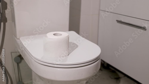 Woman putting toilet paper roll on restroom bowl. Hygiene maintenance for intestinal health and prevention of discomfort. Medical awareness for screening of hemorrhoid and colorectal cancer symptoms.