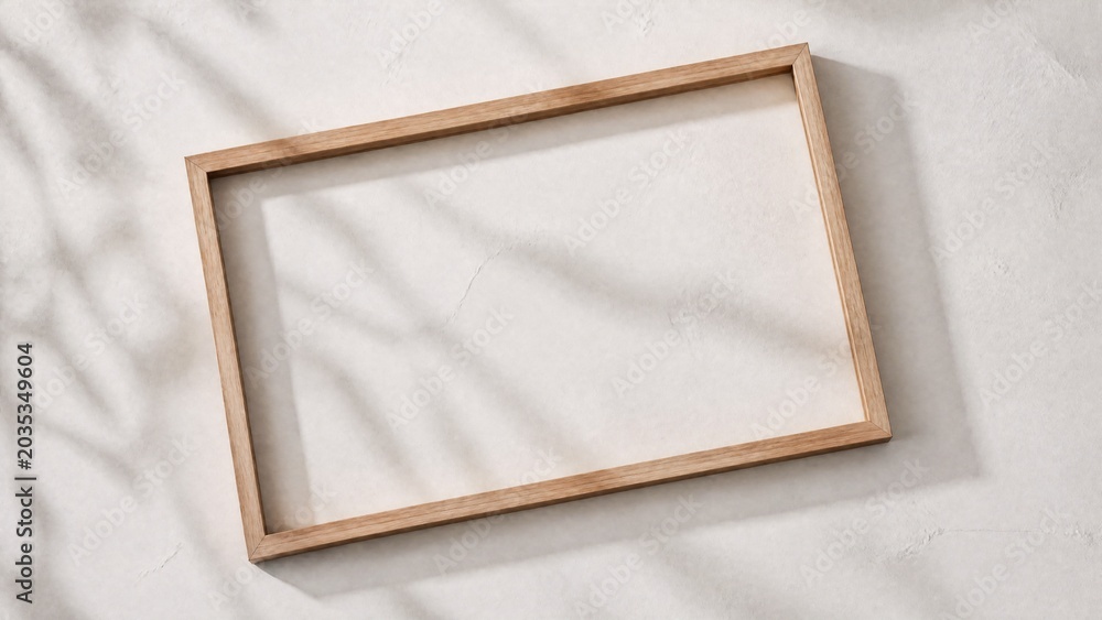 Fototapeta premium Slim wooden frame on a textured white surface, showcasing natural shadows and minimalist design.