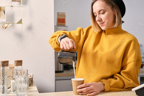 Barista pouring milk, making latte art, working at coffee shop